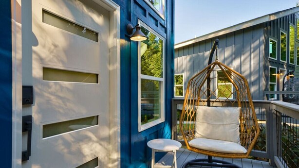 Eine Fassade in Blau und Weiß mit einem Hängestuhl und einem kleinen Tisch auf einer Holzterrasse.