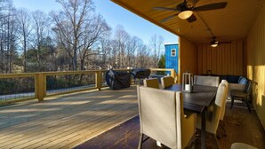 A covered outdoor deck with a dining table, chairs, and a blue structure.