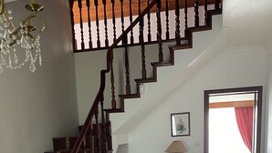 A staircase with wooden railings and red carpeted steps, leading to a room with a glass-top coffee table, a lamp, and a framed picture on the wall. - Green Tropical House ,Great view of the ocean (Ponta Delgada)