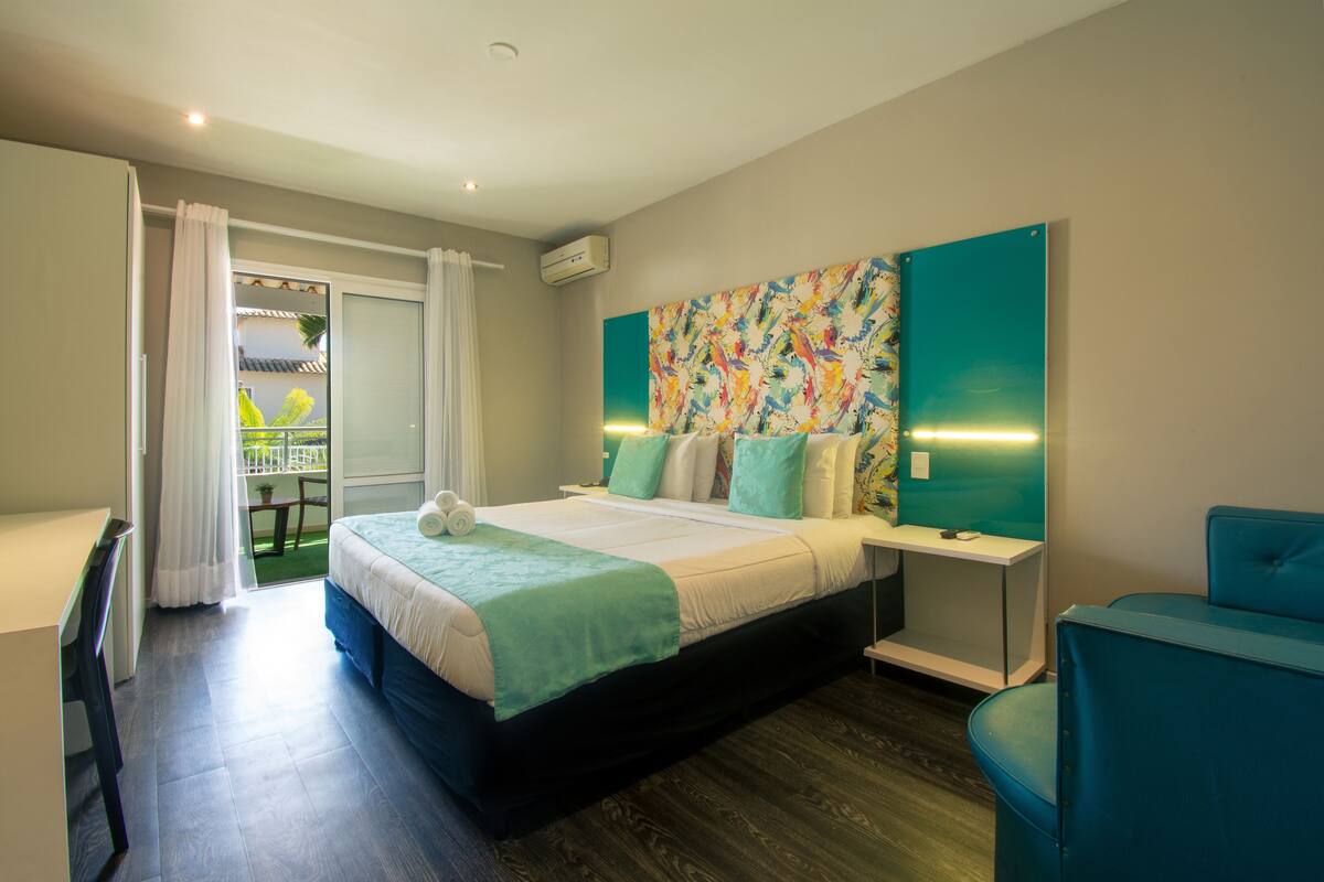 Une chambre d’hôtel moderne avec un grand lit, un bureau et une vue sur un balcon.