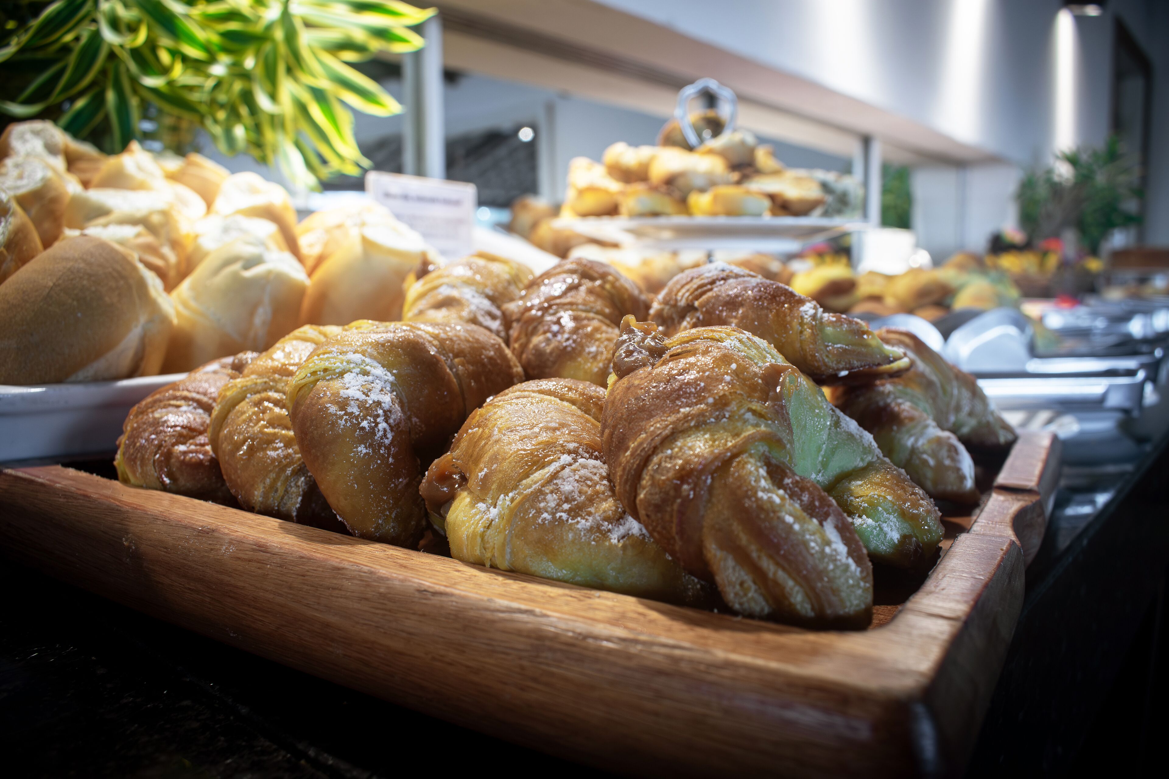 A variety of pastries displayed on wooden trays, likely in a bakery or cafe setting.