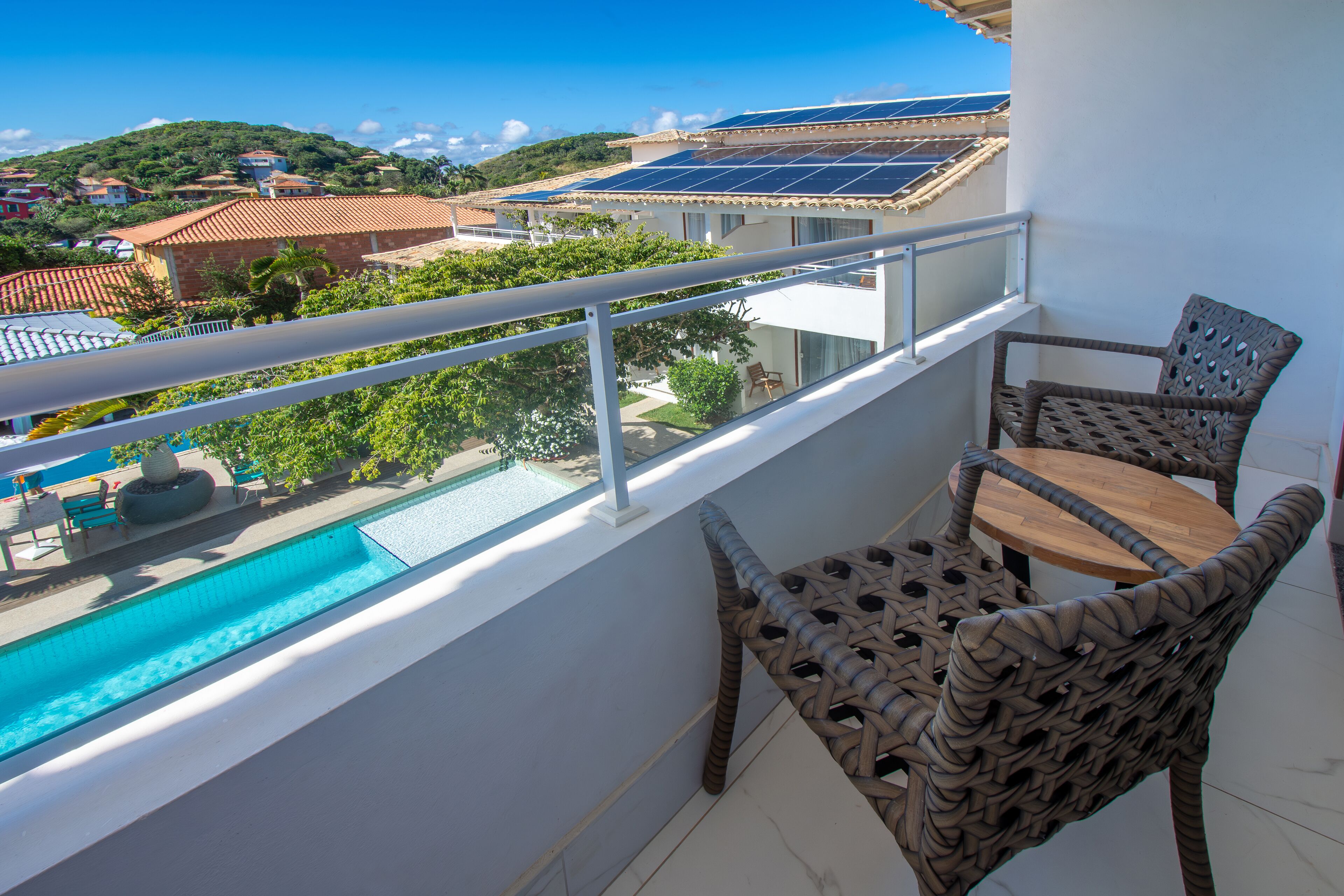 A balcony with a view of a swimming pool, solar panels, and a hillside.
