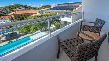 A balcony with a view of a swimming pool, solar panels, and a hillside.