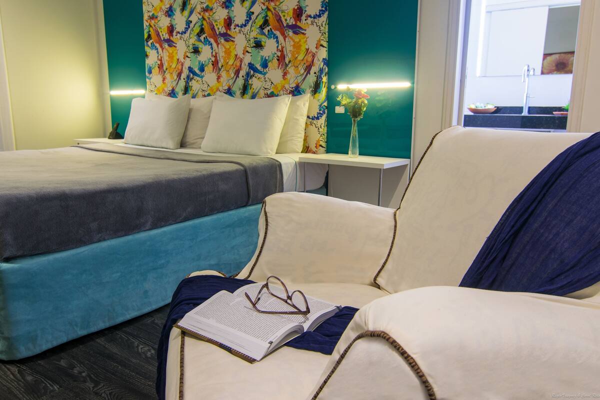 Une chambre d’hôtel avec deux lits, une table de chevet et une chaise sur laquelle se trouvent un livre et des lunettes.