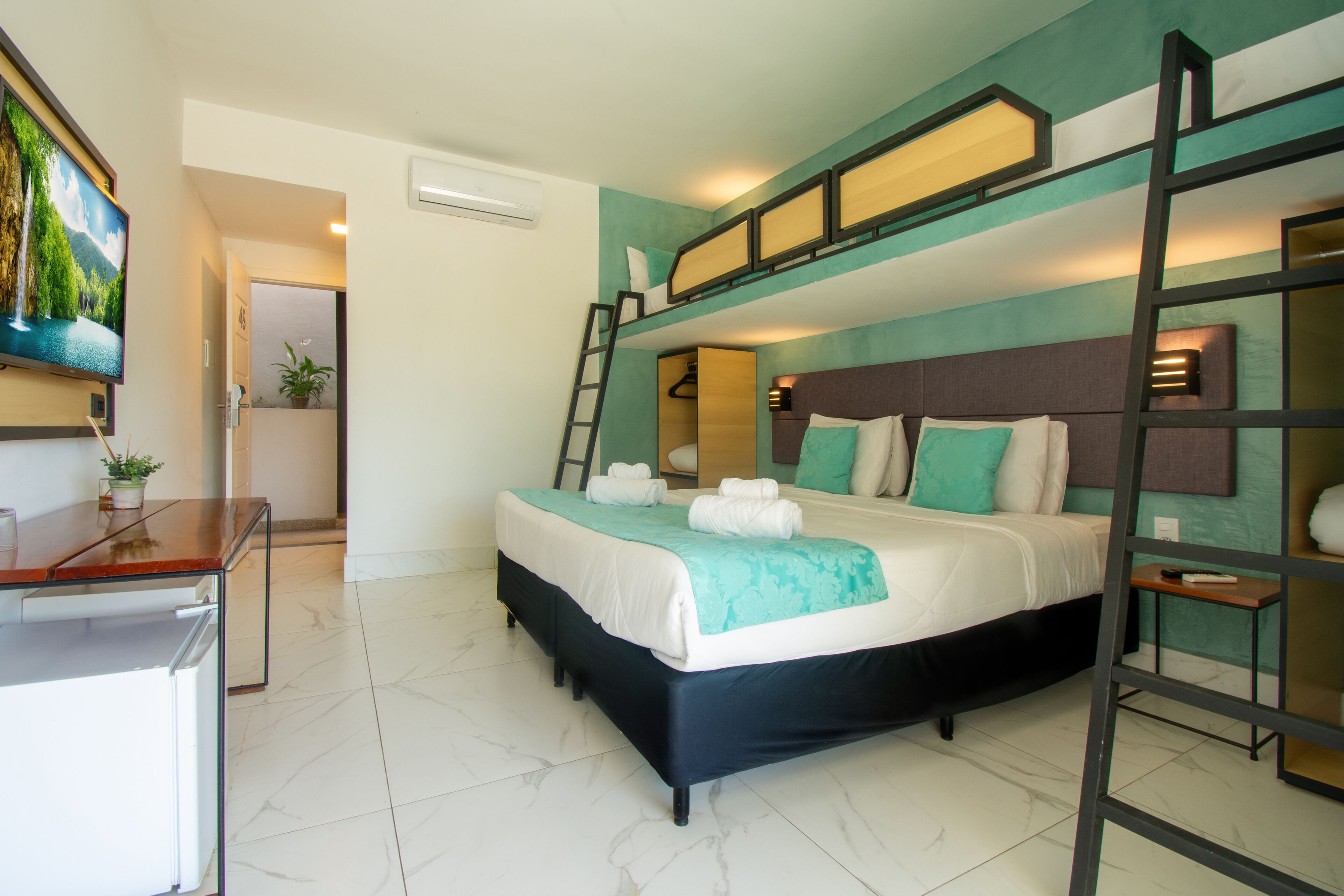 A bedroom with a bunk bed, a desk, and a TV.