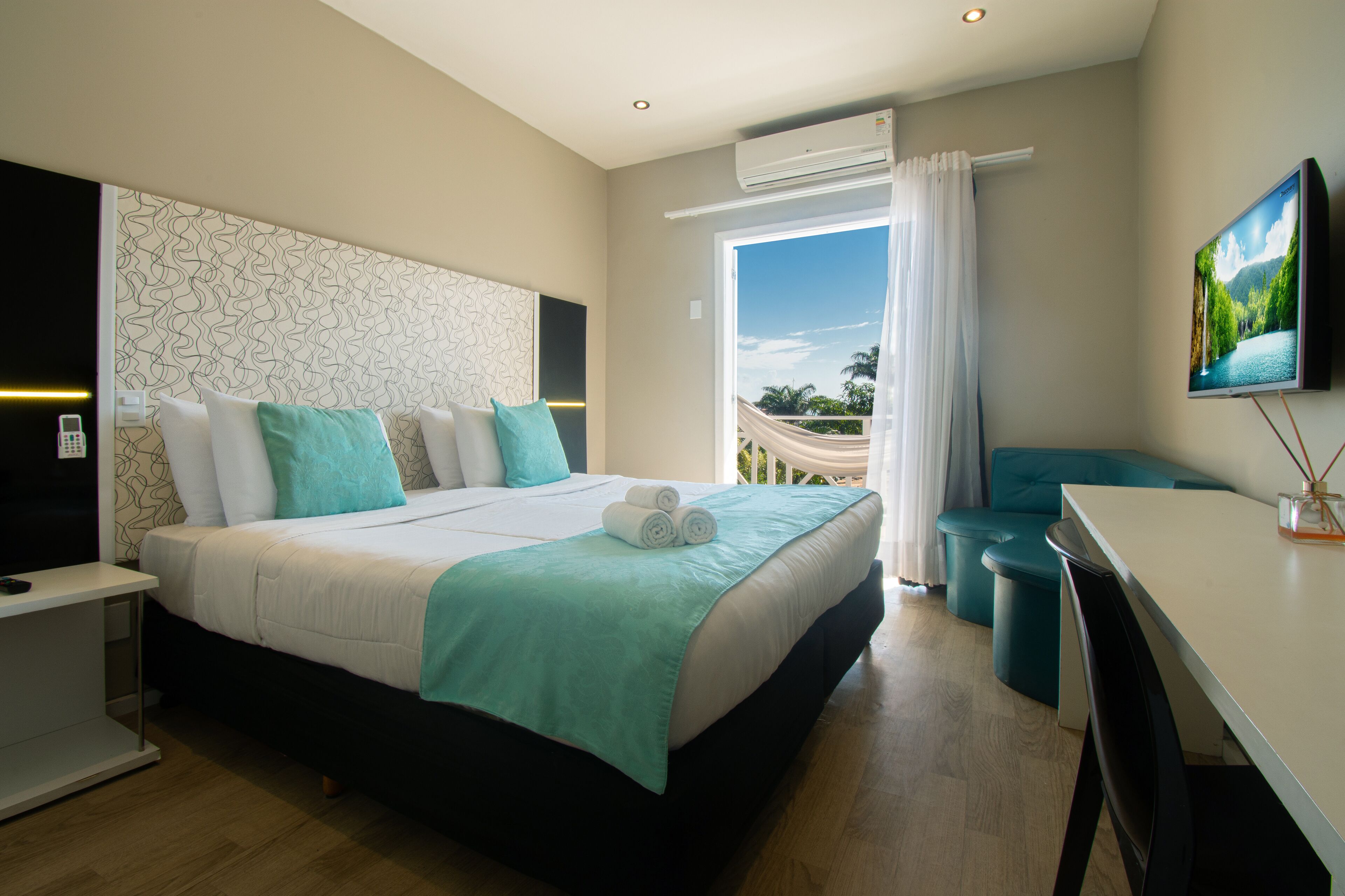 A modern hotel room with a large bed, a desk, and a TV.