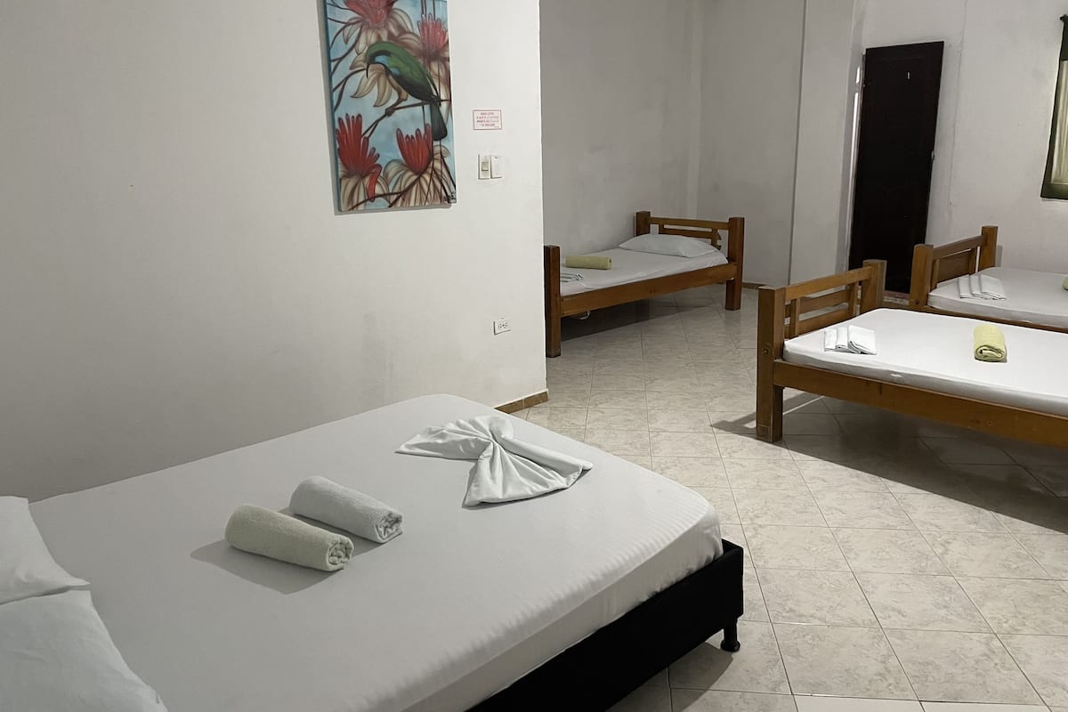 Ett hotellrum med en stor säng, en mindre säng och en enkel stol. Det finns en tavla på väggen och en dörr i bakgrunden.