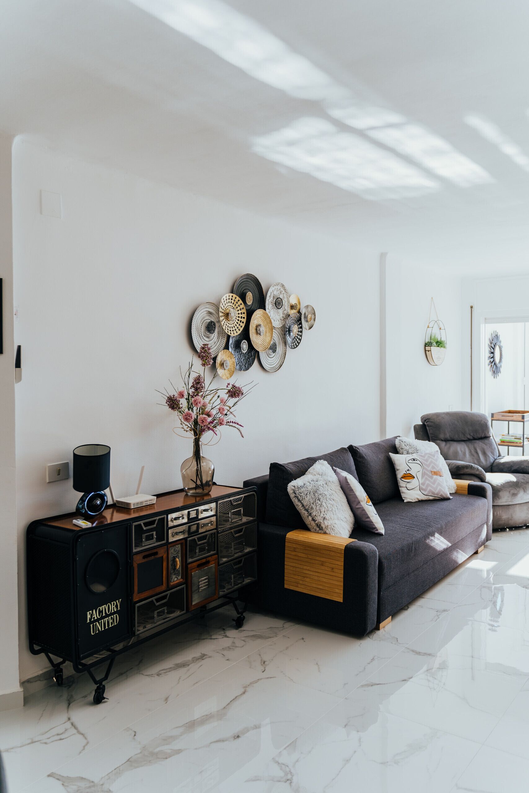 Ein modernes Wohnzimmer mit einem schwarzen Sofa, einem Couchtisch und einer dekorativen Wandverkleidung.