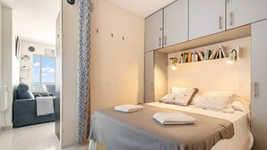 A bedroom with a bed, bedside tables, a bookshelf, and a view of the outdoors. - WELCS APARTAMENTO 053 EMP  Frente al Mar (Empuriabrava)