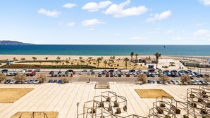 A parking lot with multiple rows of cars, a beach, and a clear sky. - WELCS APARTAMENTO 053 EMP  Frente al Mar (Empuriabrava)