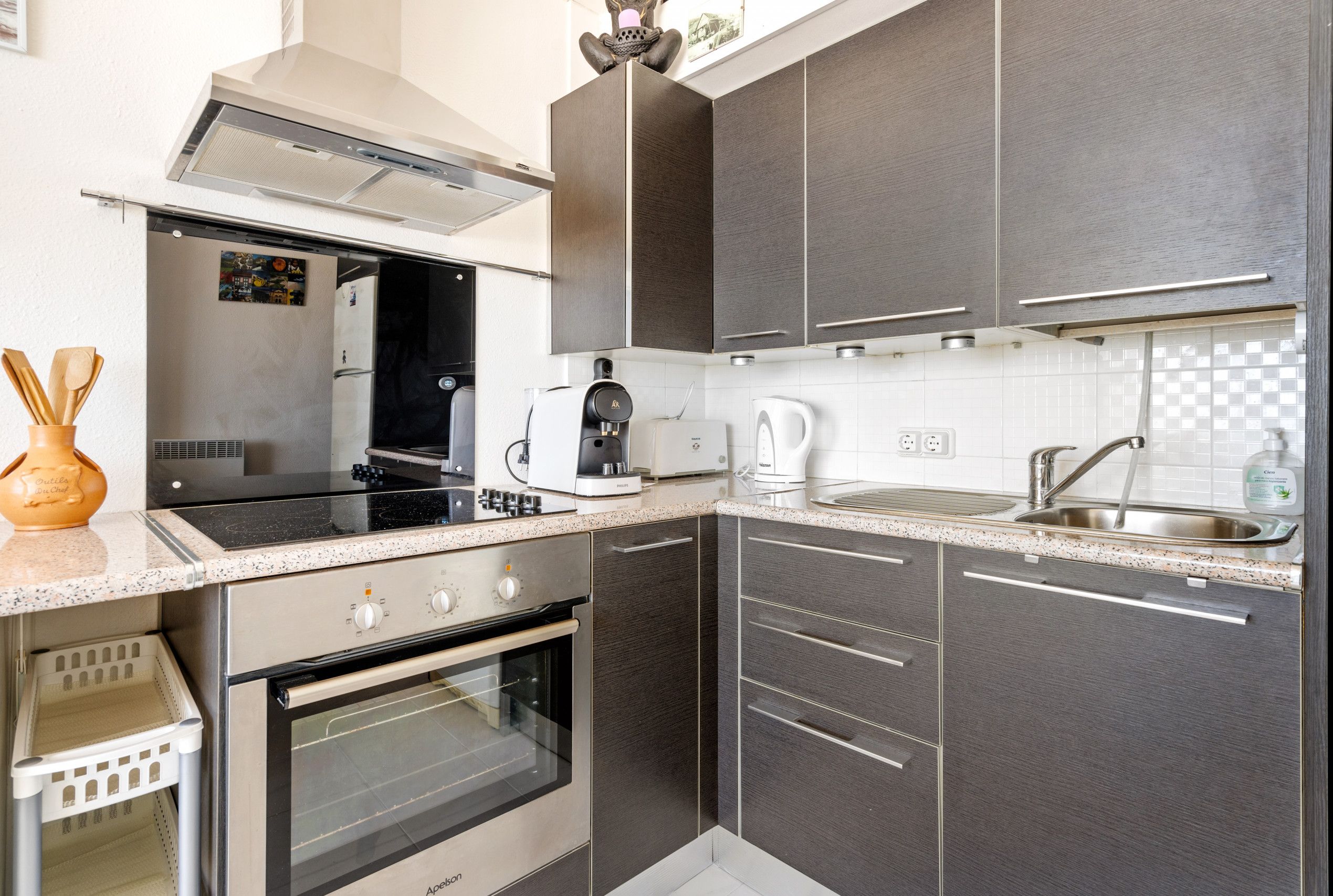 A modern kitchen with dark cabinets, stainless steel appliances, and a granite countertop.