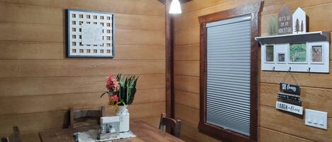 Un comedor de madera con una mesa preparada para dos personas, una planta en maceta y un letrero decorativo en la pared.