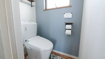 A small bathroom with a toilet, a sink, and a window.