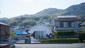 Un quartier résidentiel où se côtoient des maisons traditionnelles et modernes, avec un ciel dégagé et un paysage montagneux en toile de fond.