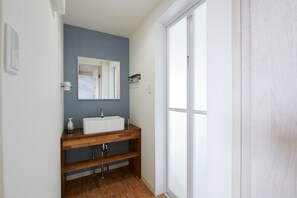 A bathroom with a white sink, a mirror, and a shower door. - Rush Awaji Guppy - Seaside Holiday Home (Awaji)