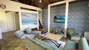 Un salon moderne doté d’un grand téléviseur, de sièges confortables et offrant une vue sur la plage.