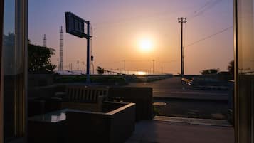 A sunset view from a balcony with outdoor seating and a street in the background.