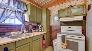 A kitchen with green cabinets, a white stove, and a sink. - Stargaze, Hike & Kayak: Cabin Near Copper Breaks! (Crowell)