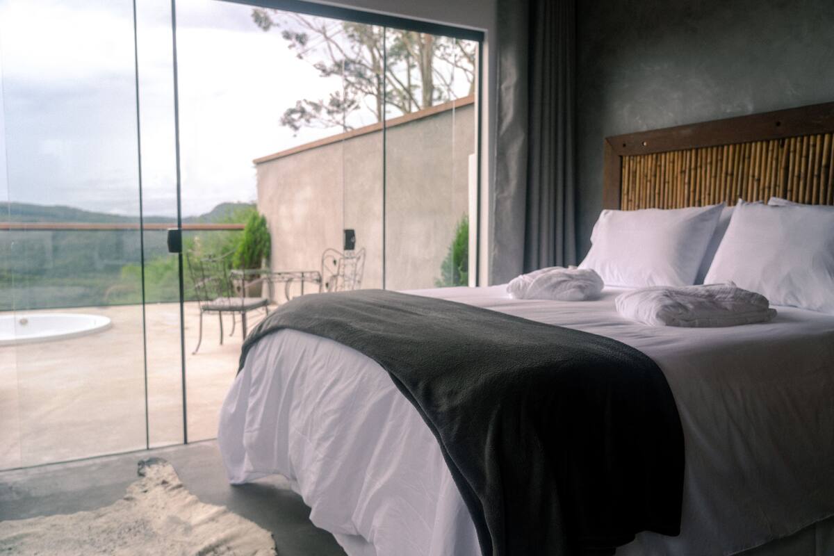 Un dormitorio moderno con una cama grande, vistas al exterior y un balcón.