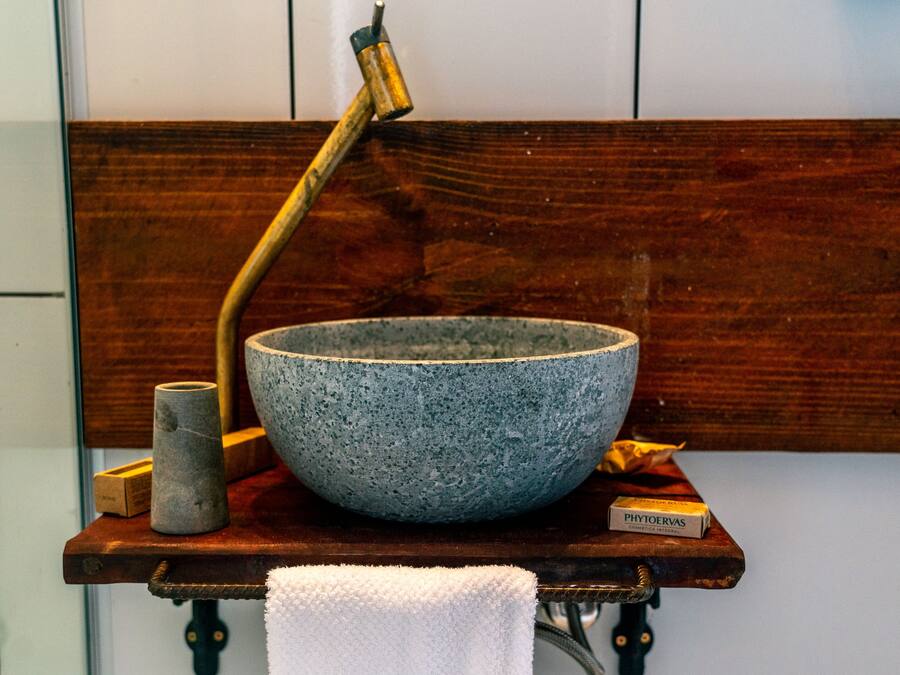 Eine rustikale Holzbank mit einer großen Steinschale, einer Metallbürste und einem kleinen Behälter darauf.