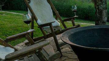 A stone patio with two wooden chairs and a black fire pit.
