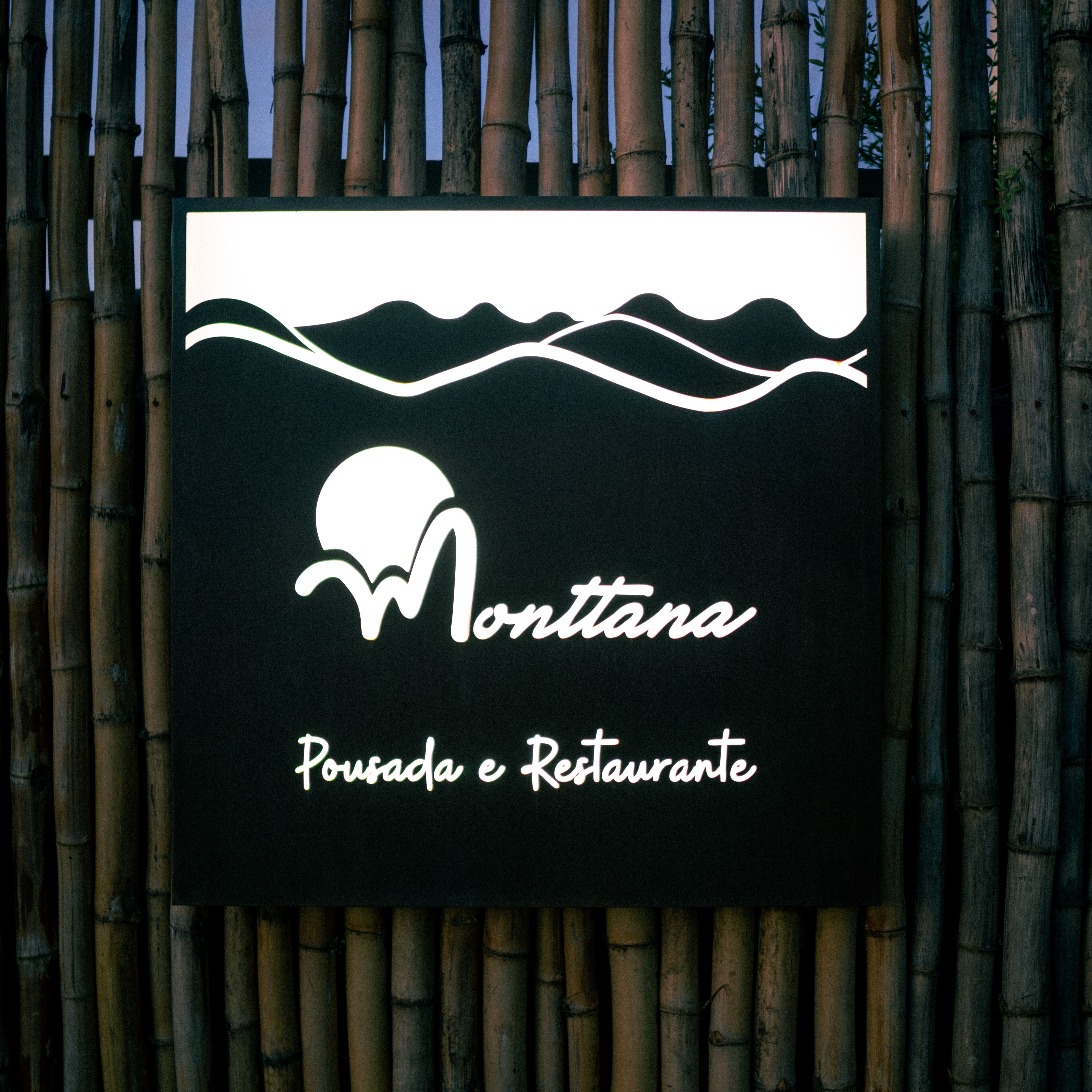 A sign with the name 'Montana Pousada e Restaurante' against a bamboo backdrop.