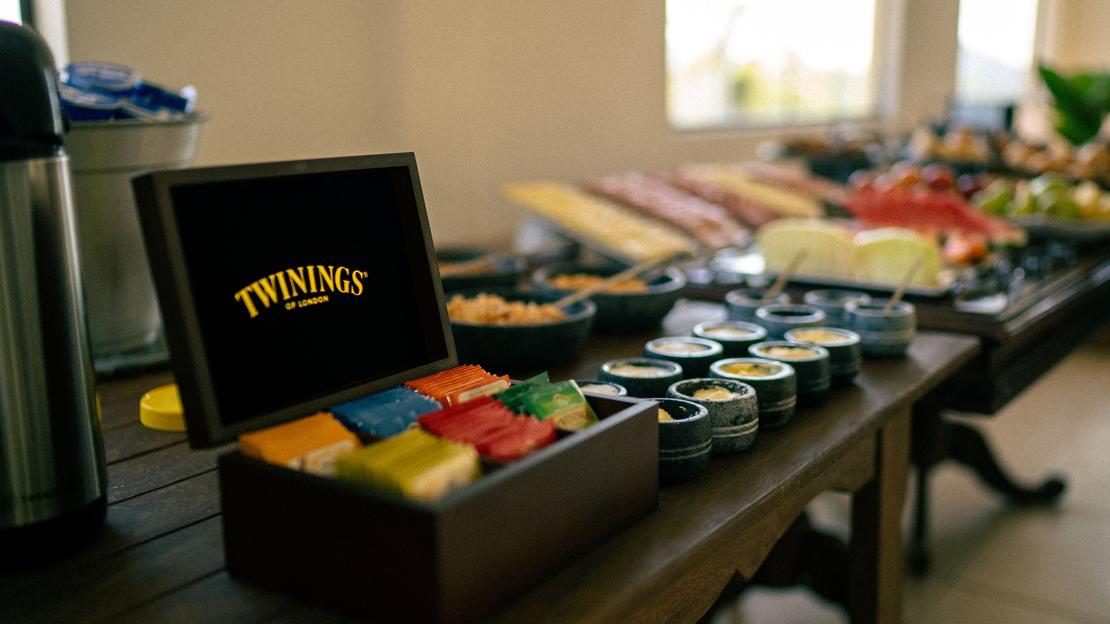 A buffet table with various food items and a sign that reads "TWININGS OF LONDON".