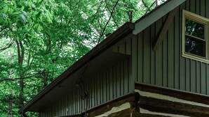 A log cabin with a porch, surrounded by a garden with rocks and plants. - Hikers Retreat in the Linville Gorge Forest (Nebo)