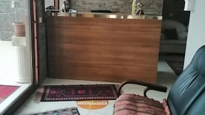 A reception area with a wooden counter, a clock, and a couch. - Melita Hotel (Urla)