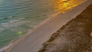A beach with a wooden walkway leading to the water, a sandy shore, and a sunset over the ocean. - Navarre Beach Regency 705 - Nama' Stay At The Beach (Navarre)