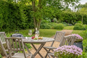 Enjoy al fresco dining in a serene garden setting, complete with a grill and beautifully manicured surroundings.