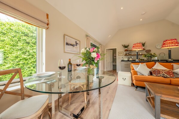 Relax in this inviting space with a glass-top dining table and comfortable sofa, surrounded by lush views and decorative touches.