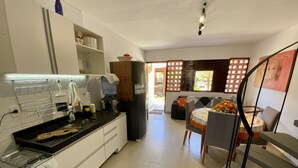A modern kitchen with a stove, sink, and a dining area with a table and chairs. - Casa duplex na Praia do Francês (Marechal Deodoro)