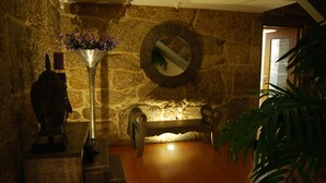 A stone wall with a round mirror, a wooden bench, and a statue. - Quinta do Passal (Pacos De Ferreira)