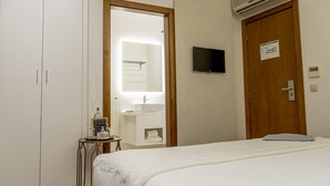 A hotel room with a bed, a small table with a bottle and a sign, a TV mounted on the wall, and a door with a sign. - Quinta do Passal (Pacos De Ferreira)