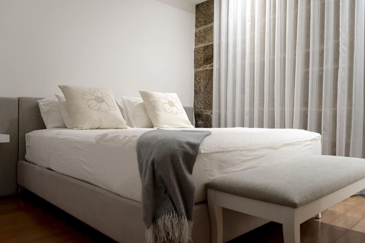 A modern bedroom with a large bed, a bedside table, and a bench.