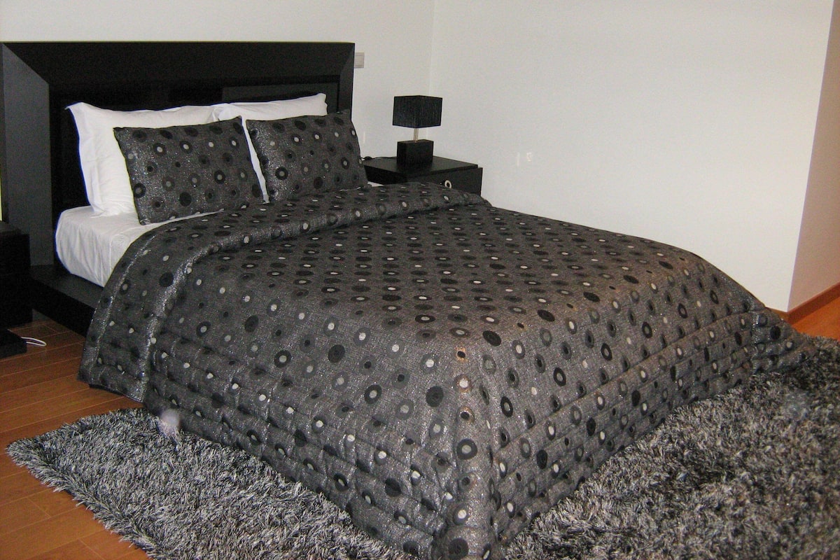 A bedroom with a bed, a nightstand, and a rug.