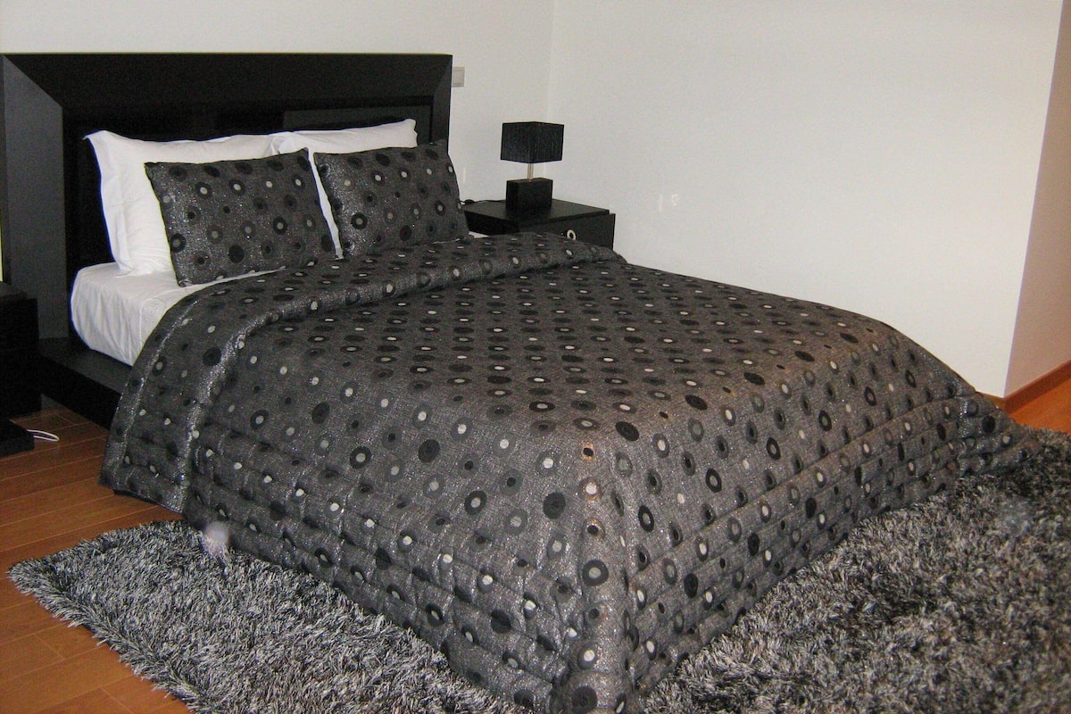 A bedroom with a bed, a nightstand, and a rug.