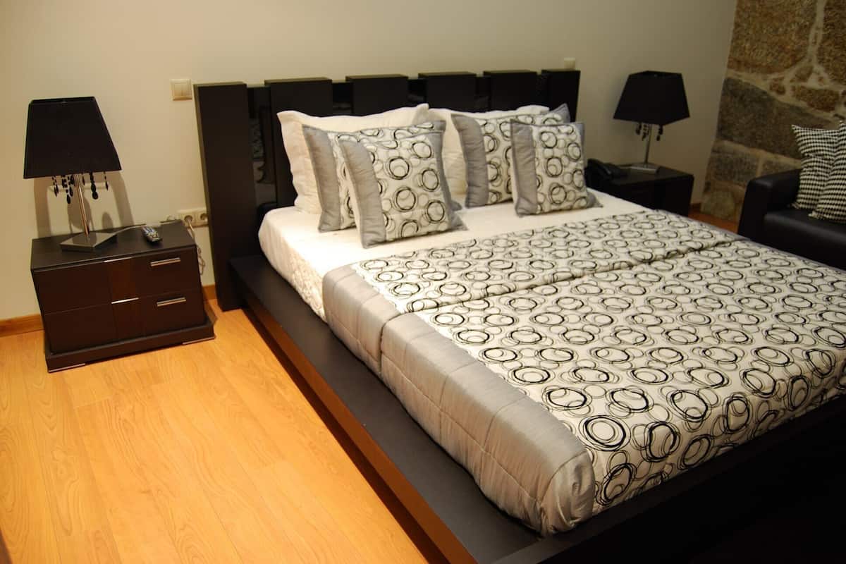 A bedroom with a bed, two bedside tables, a nightstand, and a sofa.