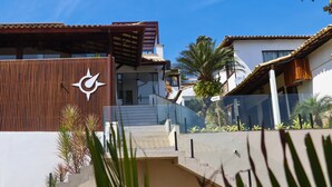 A modern building with a wooden facade, a staircase leading to a covered area, and palm trees in the background. - Gammel Dansk by Latitud Hoteles (Búzios)