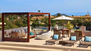 A rooftop terrace with wicker furniture, a wooden pergola, and a view of a coastal town. - Gammel Dansk by Latitud Hoteles (Búzios)
