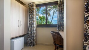 A compact kitchen with a refrigerator, a chair, and a window with curtains. - Gammel Dansk by Latitud Hoteles (Búzios)