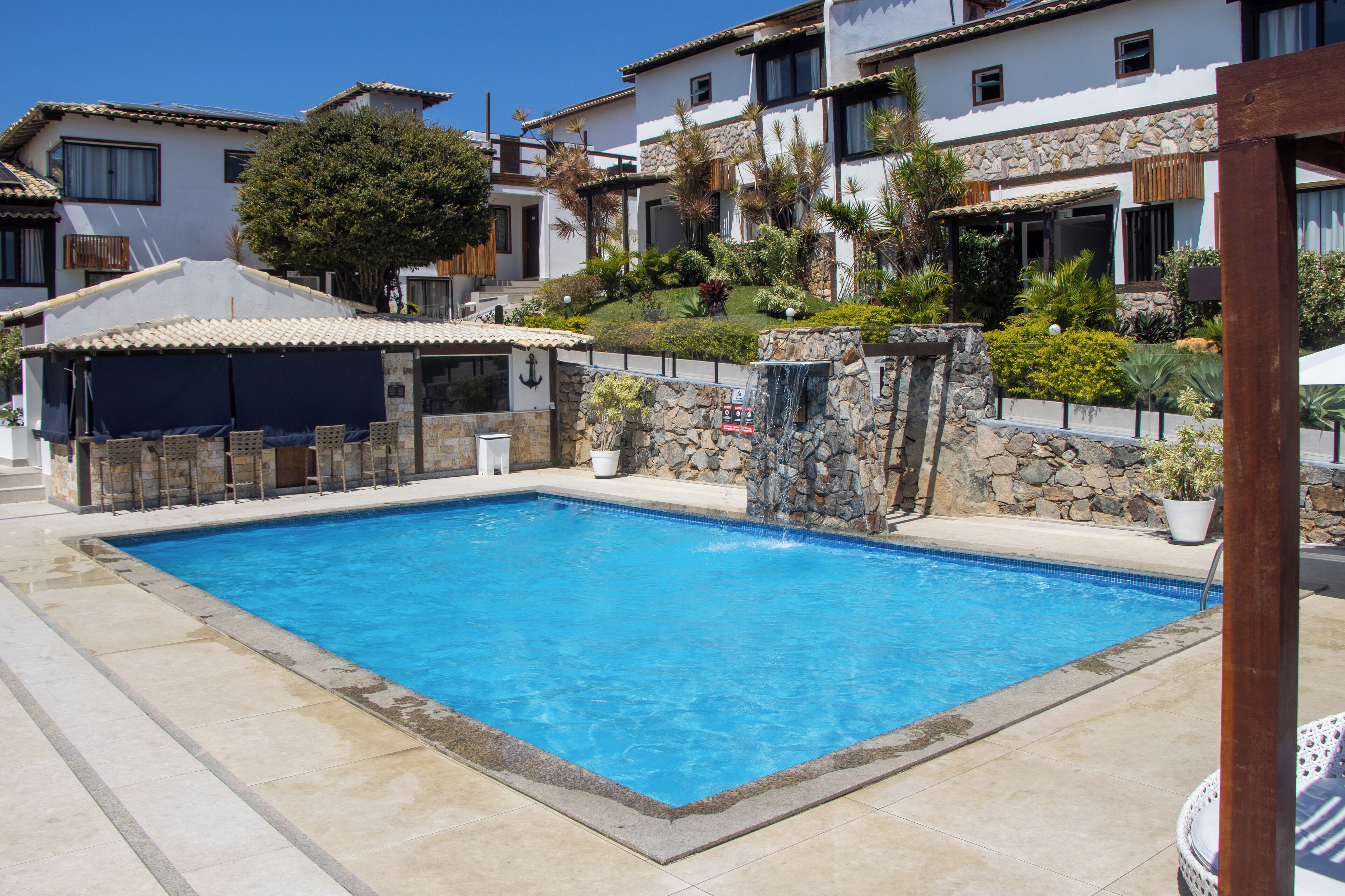 A swimming pool surrounded by stone walls and a covered seating area.