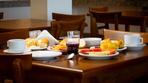 A dining table with plates of food, cups, and a glass of juice. - Gammel Dansk by Latitud Hoteles (Búzios)