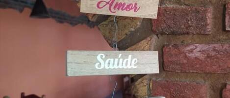 Un letrero de madera con palabras en portugués sobre un muro de ladrillo.