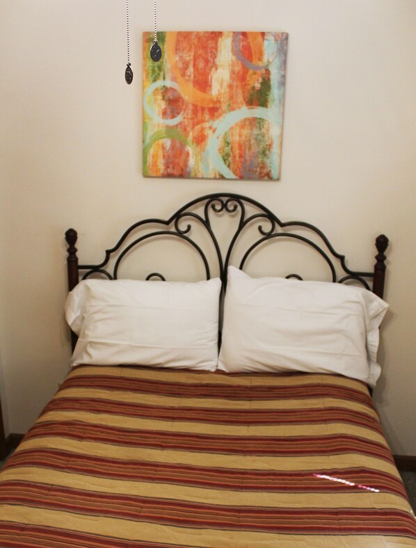 A bed with a striped bedspread, two white pillows, and a black metal headboard.
