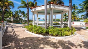 A covered outdoor area with lounge chairs, a pool, and palm trees. - Panoramic Lagoon Studio · Water Backup (San Juan)
