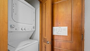 A laundry room with a white washer and dryer, a wooden door, and a map on the wall. - Panoramic Lagoon Studio · Water Backup (San Juan)
