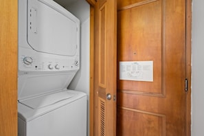 A laundry room with a white washer and dryer, a wooden door, and a map on the wall. - Panoramic Lagoon Studio + Resort Pool (San Juan)