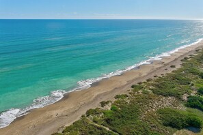 Een kustlandschap met een zandstrand en helder turquoise water.